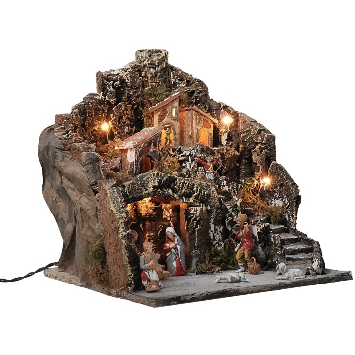 Belén iluminado con pueblo en la montaña completo de estatuas