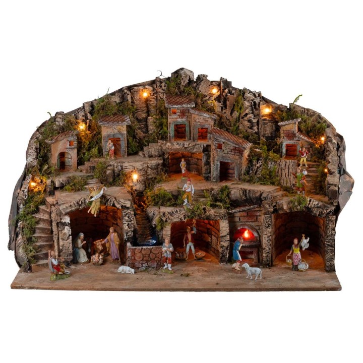 Illuminated nativity scene with caves, little houses, stream