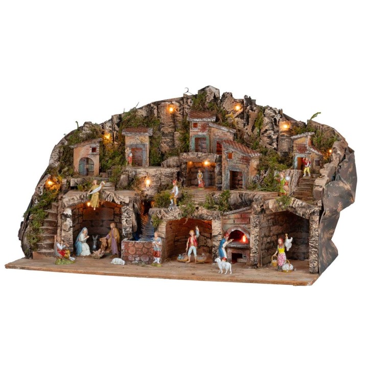 Illuminated nativity scene with caves, little houses, stream