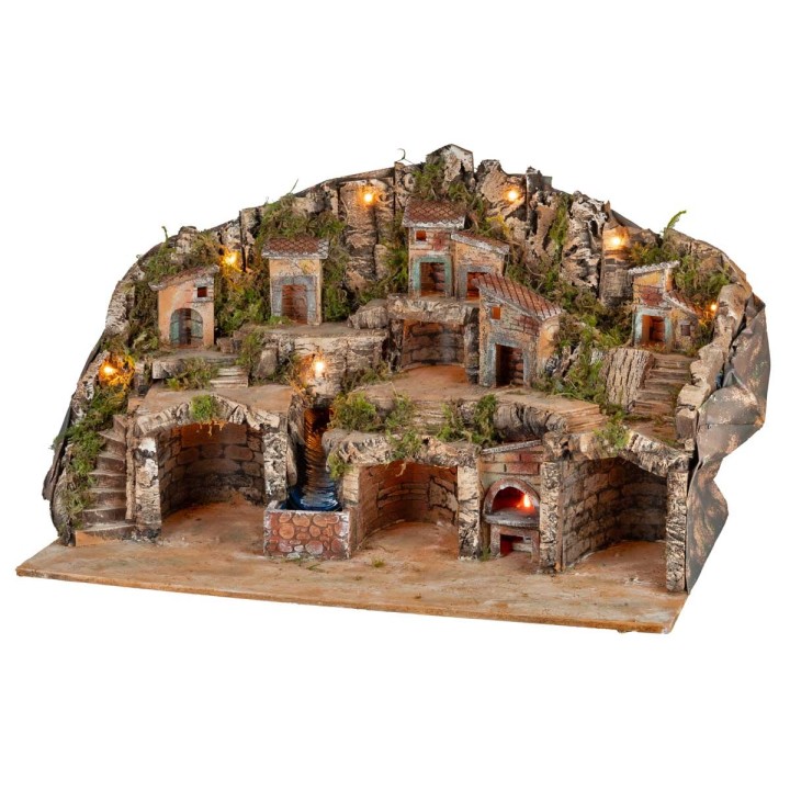 Illuminated nativity scene with caves, little houses, stream