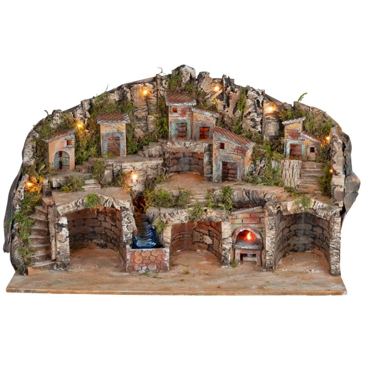 Belén iluminado con cuevas, casitas, arroyo y horno en