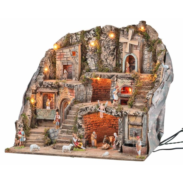 Illuminated nativity scene with statues, fountain, fire, and