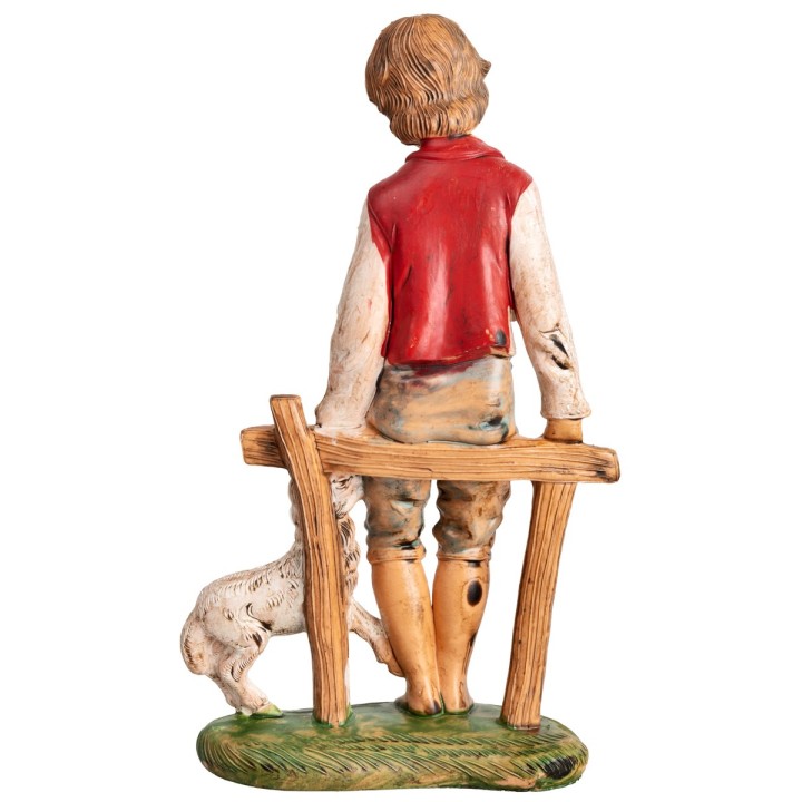 Boy sitting on a fence with a little sheep h 18 cm
