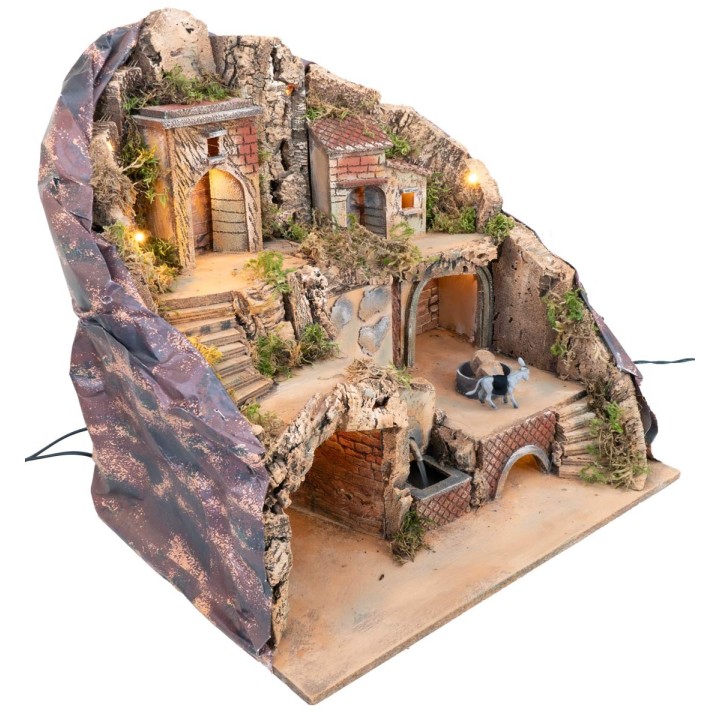 Illuminated nativity scene with fountain and moving donkey at